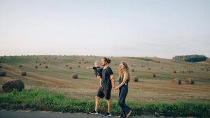 A joyful family walking hand in hand across a picturesque hayfield landscape at sunset.