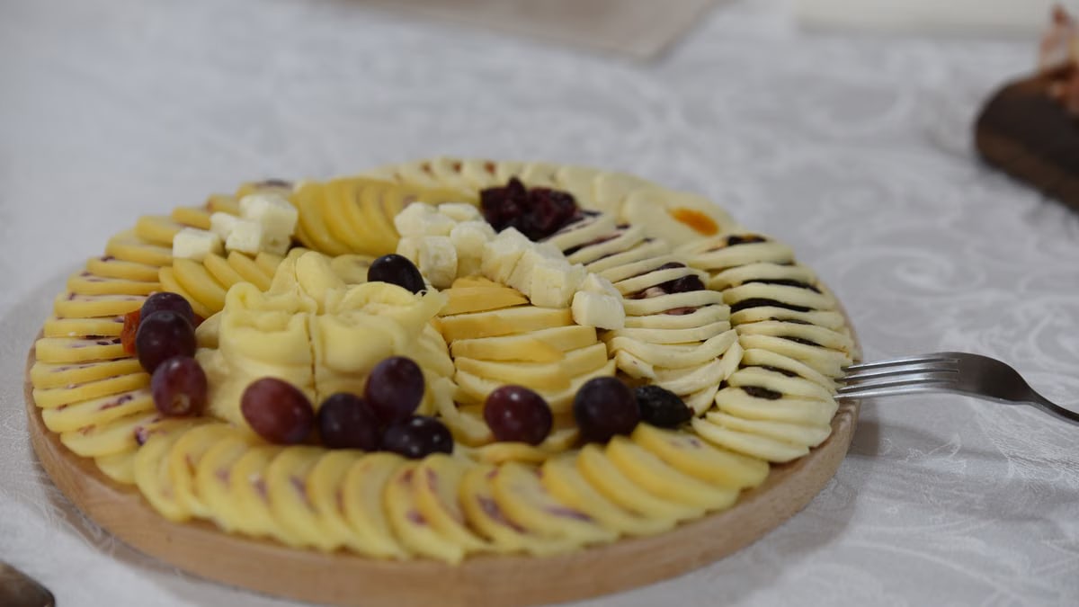 A beautifully arranged cheese platter with grapes and rustic decor, perfect for events.